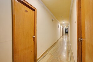 Un pasillo de hotel con puertas de madera, suelo de mármol e iluminación empotrada.