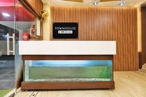 Un mostrador de recepción con un letrero que indica servicio OYO, una pared de madera y un acuario.