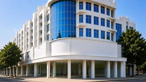 A modern multi-story building with a curved facade, large windows, and a flat roof.