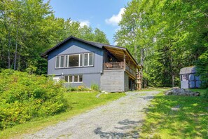 A two-story cabin with a balcony, surrounded by dense forest. - 1 Mi to Mount Snow! Classic Chalet w/ Hot Tub (West Dover)