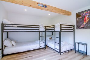 Ein Schlafraum mit Etagenbetten, Holzboden und Wanddeko zum Thema Skifahren.