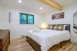 A bedroom with a bed, a bedside table with a lamp, a window, and a painting on the wall. - 1 Mi to Mount Snow! Classic Chalet w/ Hot Tub (West Dover)