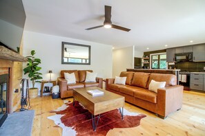 Una sala de estar moderna con un sofá de cuero marrón, una mesa de centro de madera y un tapete de piel de vaca.