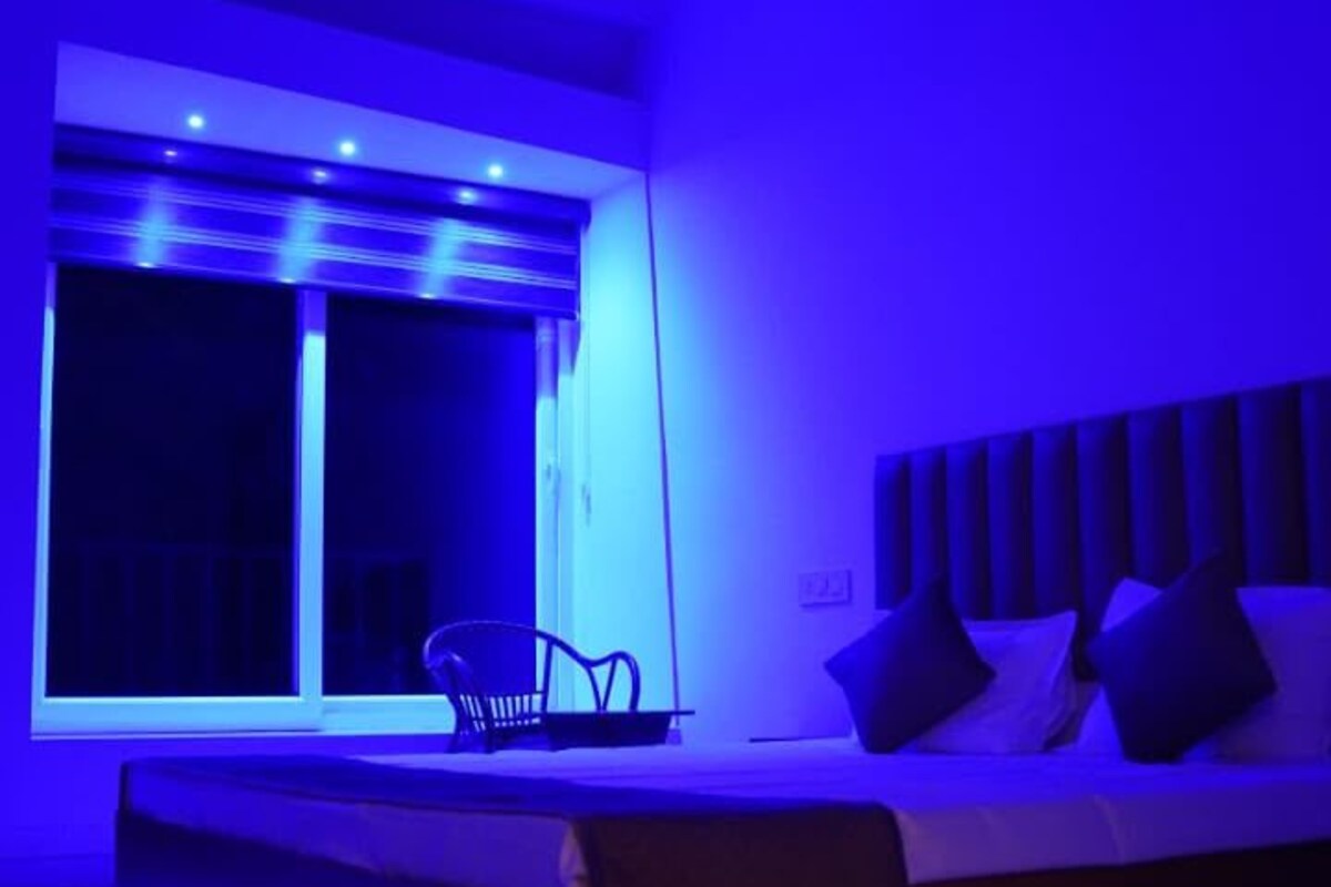 Una habitación con una cama, una silla, un ventilador de techo y una ventana.
