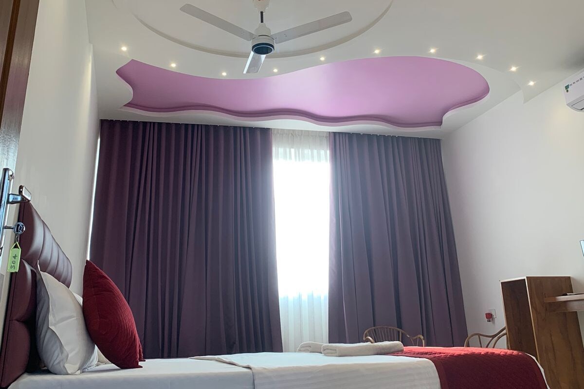 Un dormitorio con una cama, un ventilador de techo y una ventana con cortinas.