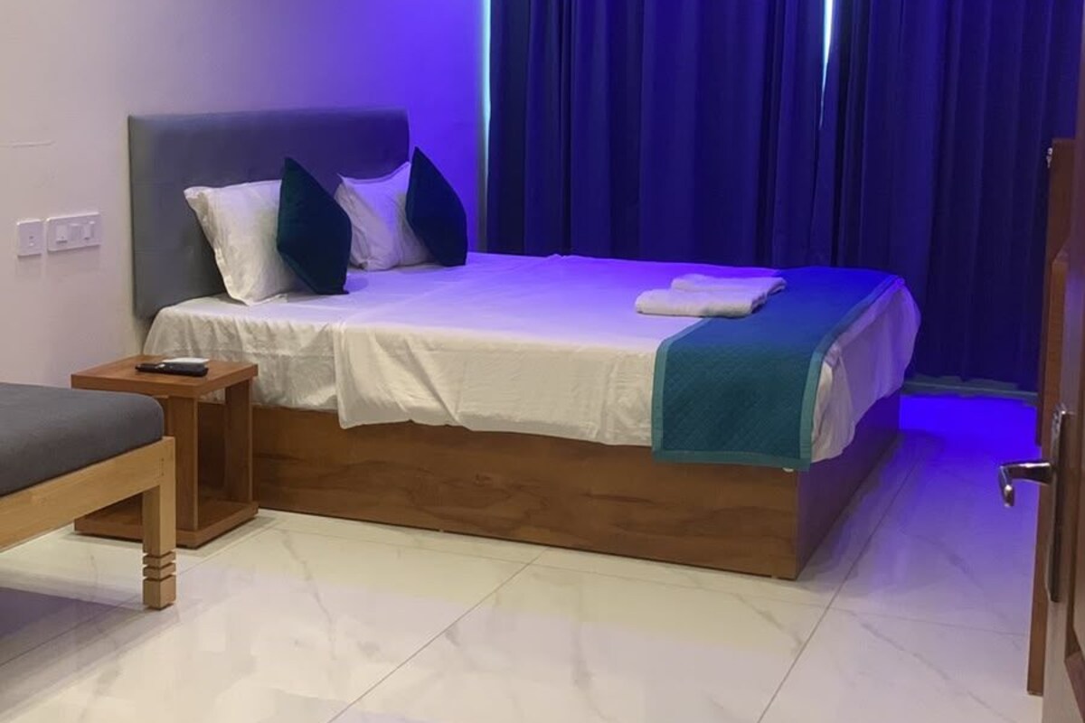 Un dormitorio con cama, mesita de noche, silla y ventilador de techo.