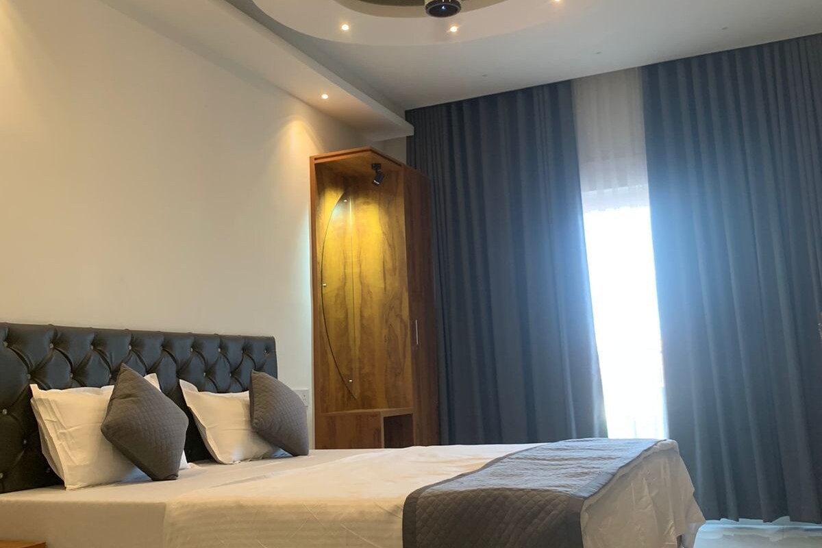 Un dormitorio moderno con cabecera capitonada, estructura de cama de madera e iluminación empotrada en el techo.