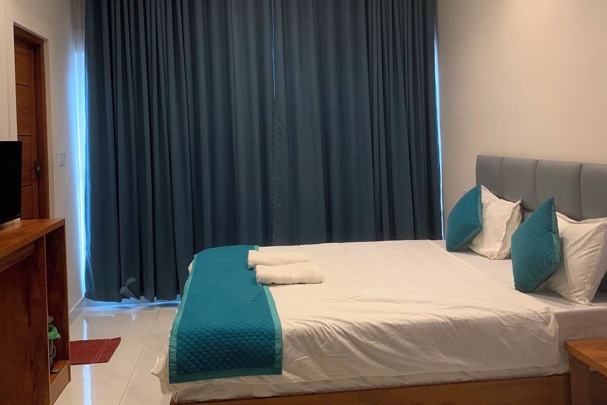 Un dormitorio con cama, ventilador de techo y un gran ventanal con cortinas.