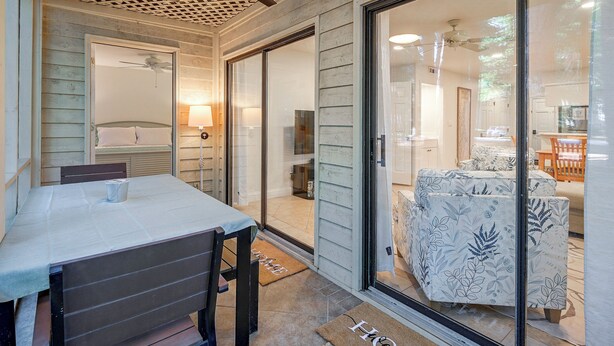 A room with a bed, a table, and a chair, with a view of another room through a glass door. - Pawleys Island Golf + Beach Getaway w/ Pool Access (Pawleys Island)