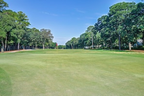 A golf course with a flagstick, trees, and a clear sky. - Pawleys Island Golf + Beach Getaway w/ Pool Access (Pawleys Island)