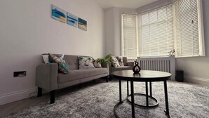 A living room with a sofa, a coffee table, and a radiator. - Stylish 3BR House in Newham East London (Greater London)