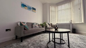 A living room with a sofa, a coffee table, and a radiator. - Stylish 3BR House in Newham East London (Greater London)
