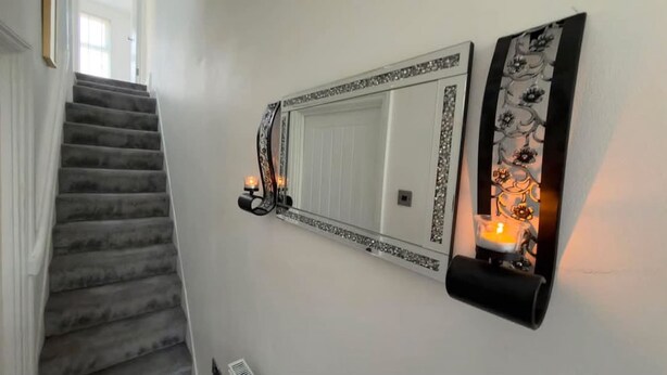 A staircase leading to a landing with a wall-mounted mirror and candle sconces. - Stylish 3BR House in Newham East London (Greater London)