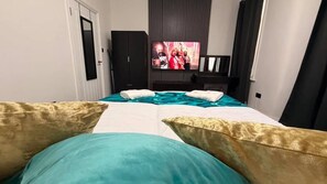 Een hotelkamer met een bed, twee kussens, een televisie en een kledingkast.