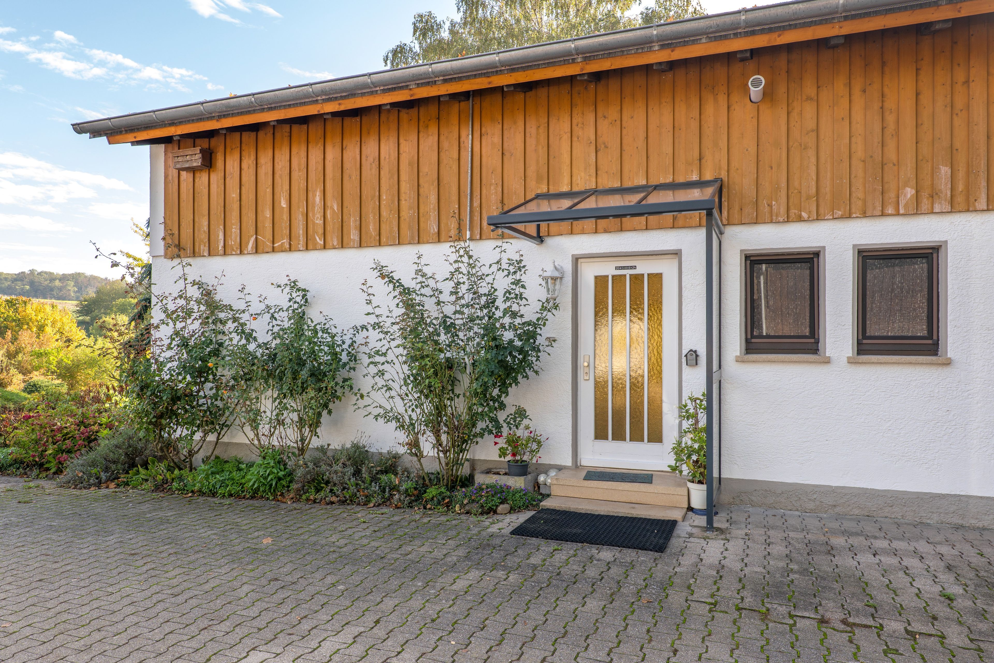 A building with a wooden facade, a white door with a glass panel, and a small porch area.