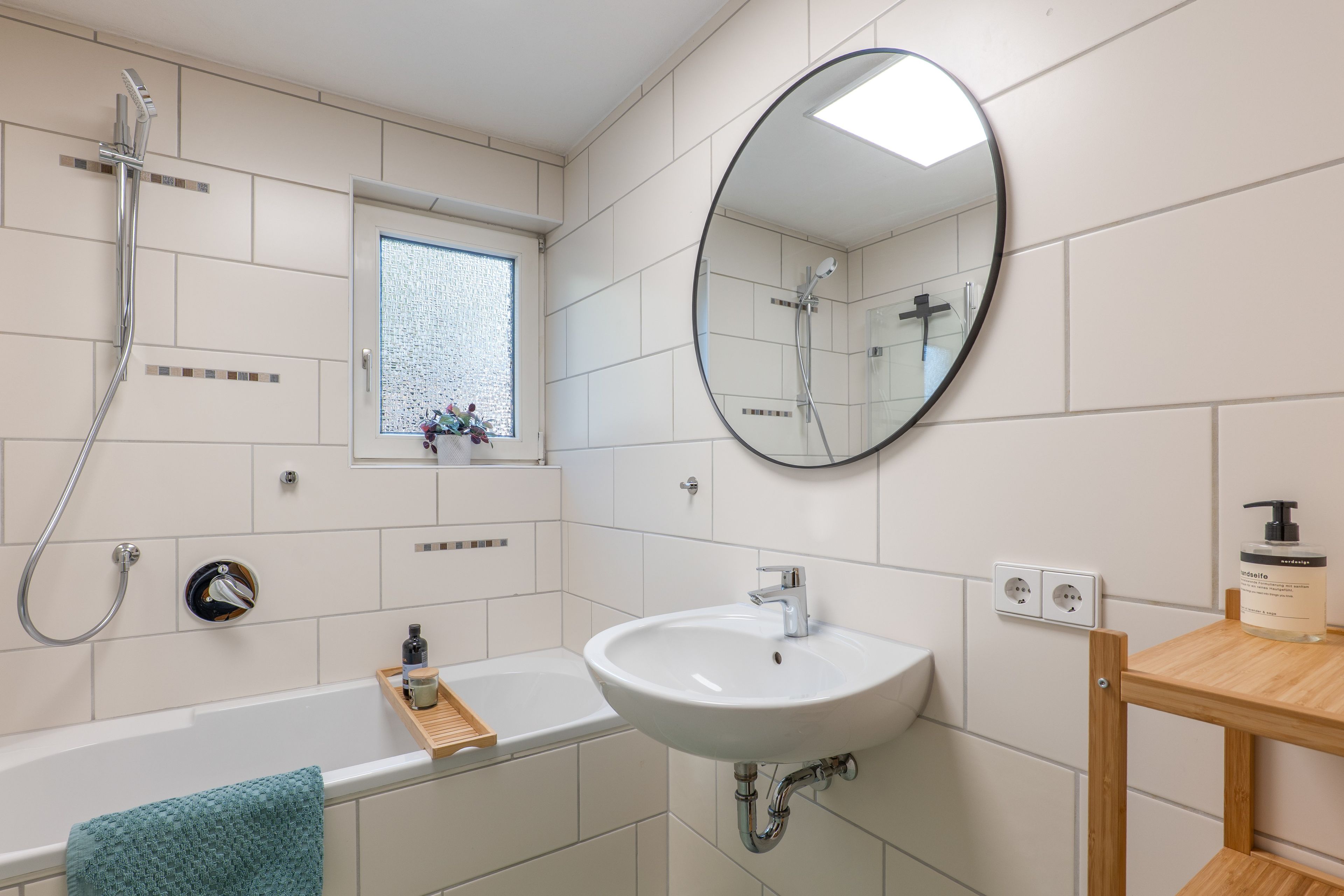A bathroom with a bathtub, a sink, a mirror, and a shower.