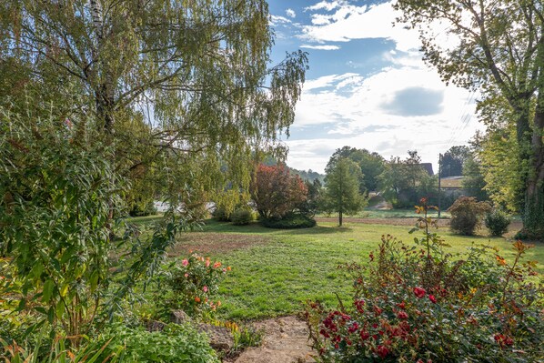 A garden with various plants and flowers, a pathway, and a distant view of a building.