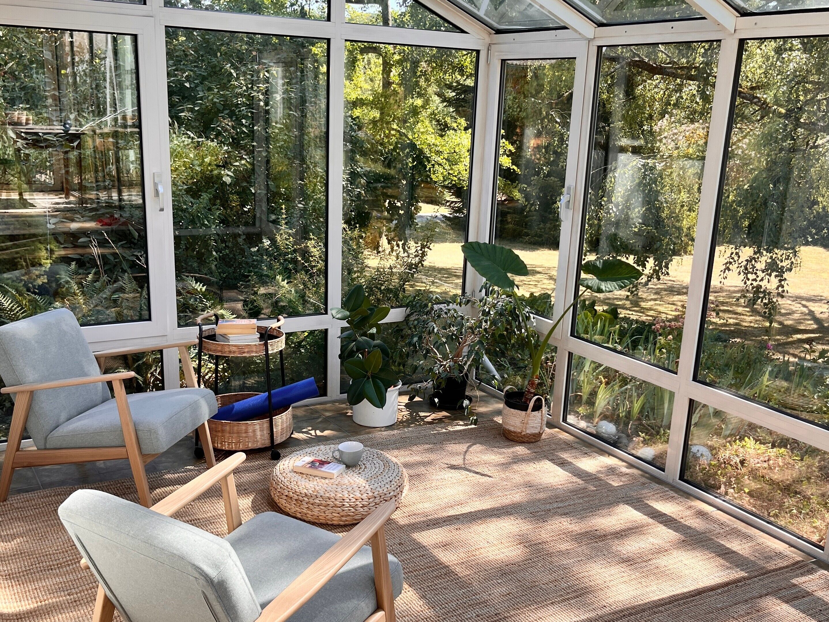 A conservatory with a glass ceiling, wooden furniture, and potted plants.