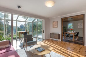 A spacious living area with large windows, a dining table, and a cozy seating arrangement.