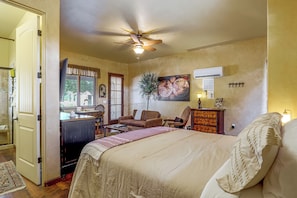 A bedroom with a bed, a desk, a chair, a dresser, and a ceiling fan.