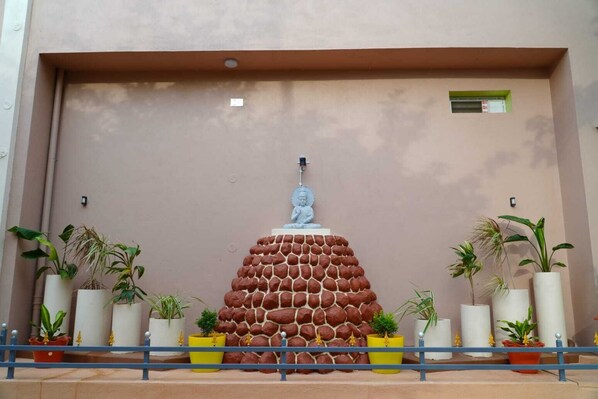 A Buddha statue on a rock formation with potted plants around it.