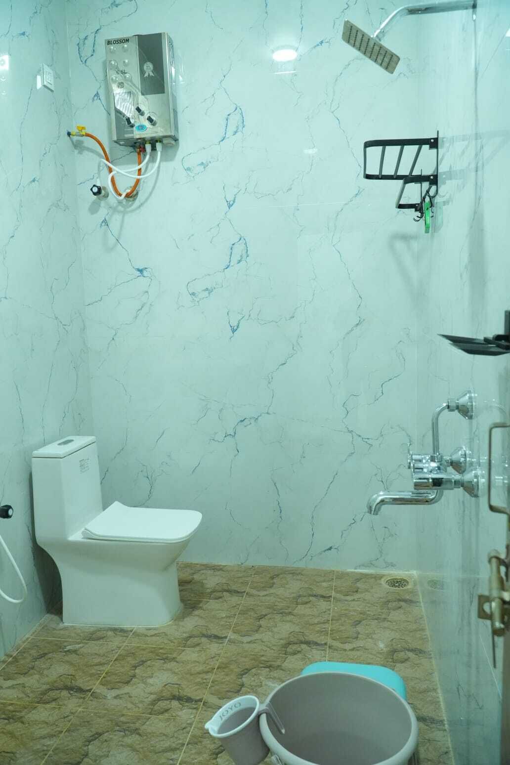 A bathroom with a toilet, shower, and a water heater mounted on the wall.