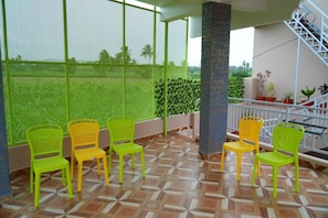 A covered outdoor seating area with chairs and a patterned floor.