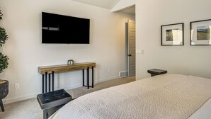 A bedroom with a bed, a TV mounted on the wall, a bedside table, and a small plant. - Hot Tub, Group Hub, Close to Deer Valley (Heber City)