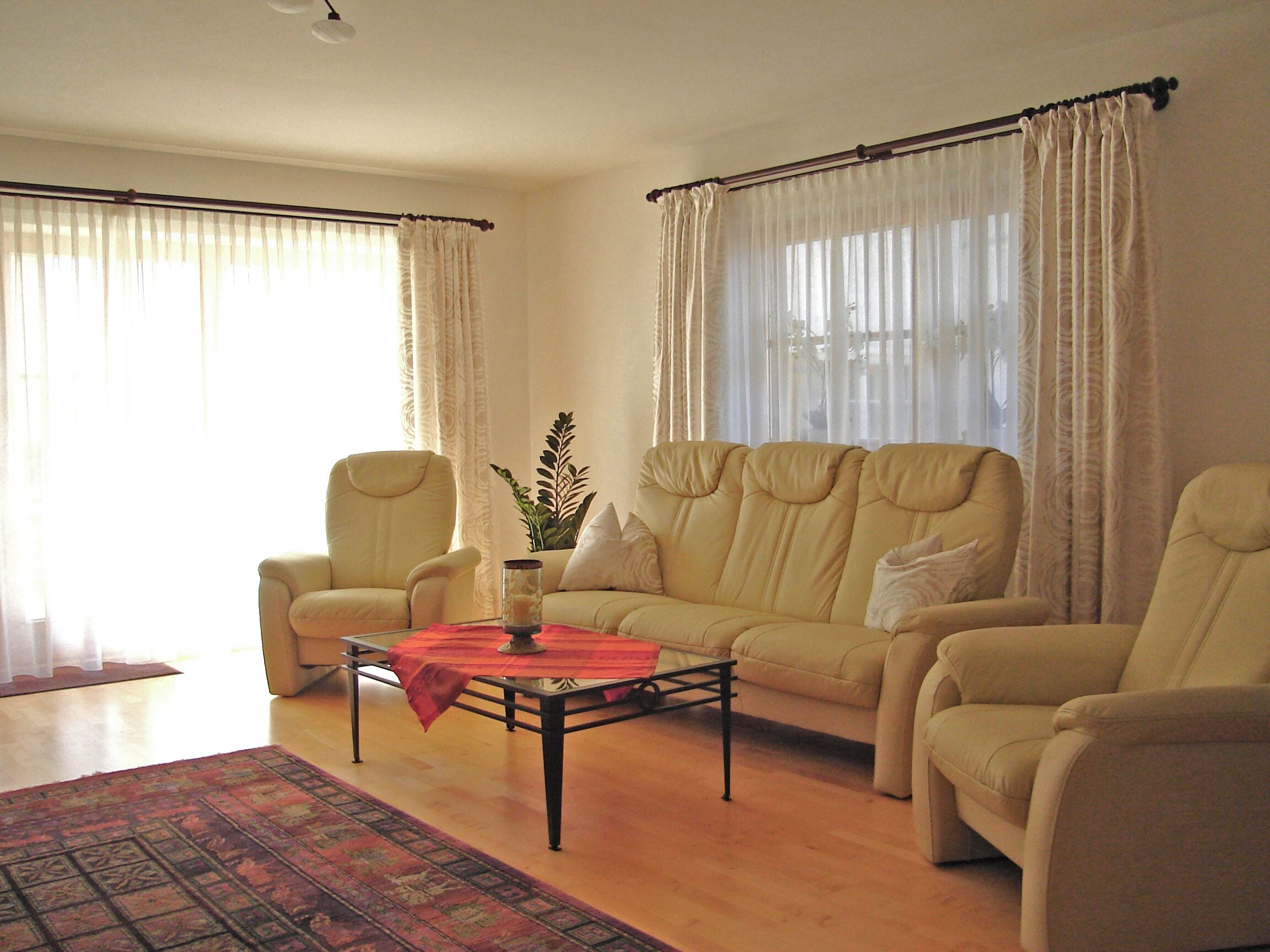 A living room with a sofa set, armchairs, a coffee table, and a rug.