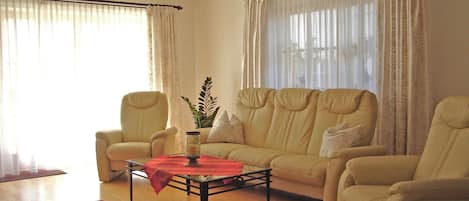 A living room with a sofa set, armchairs, a coffee table, and a rug.