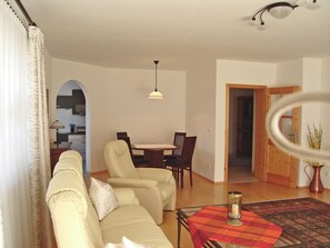Un salon comprenant un canapé, une table à manger avec des chaises, une table basse et un luminaire suspendu.