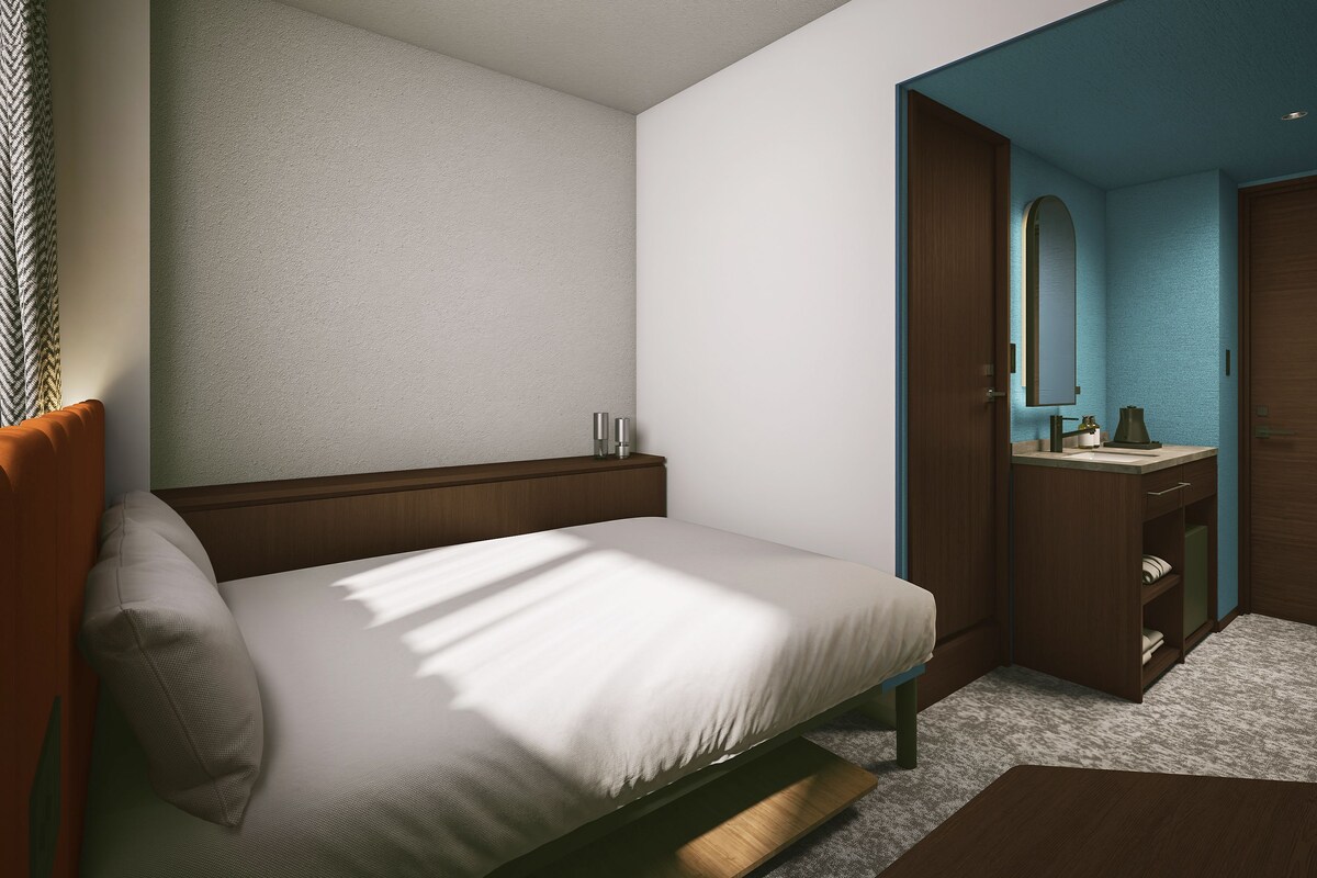 Un dormitorio moderno con una cama, una mesita de noche y un baño visible a través de una puerta abierta.