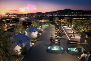 Una terraza en la azotea con piscina, espacios para sentarse y vistas a la ciudad al atardecer.