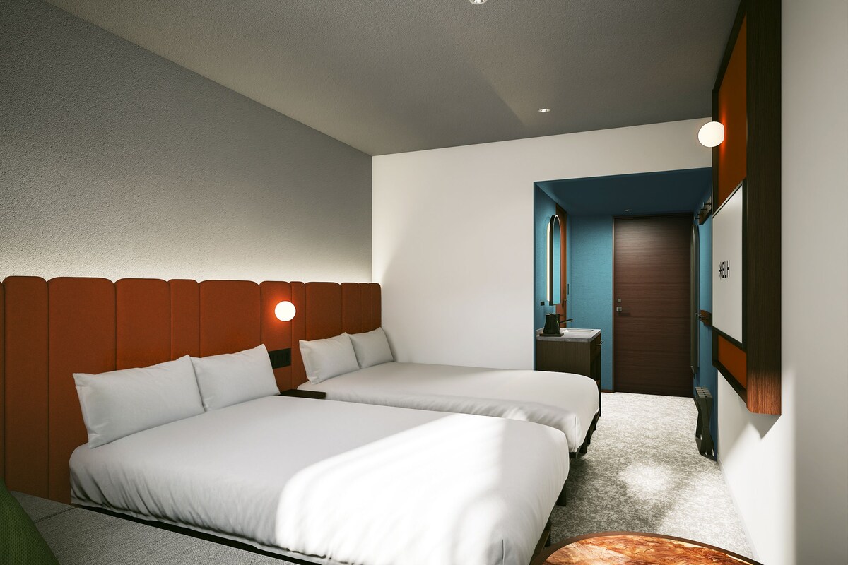 Una habitación de hotel con dos camas, baño y vista a la calle.
