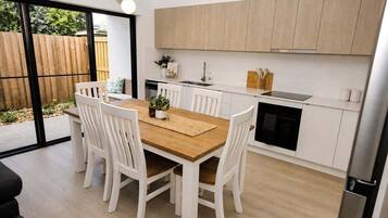 A modern kitchen with white cabinetry, a wooden dining table, and chairs.