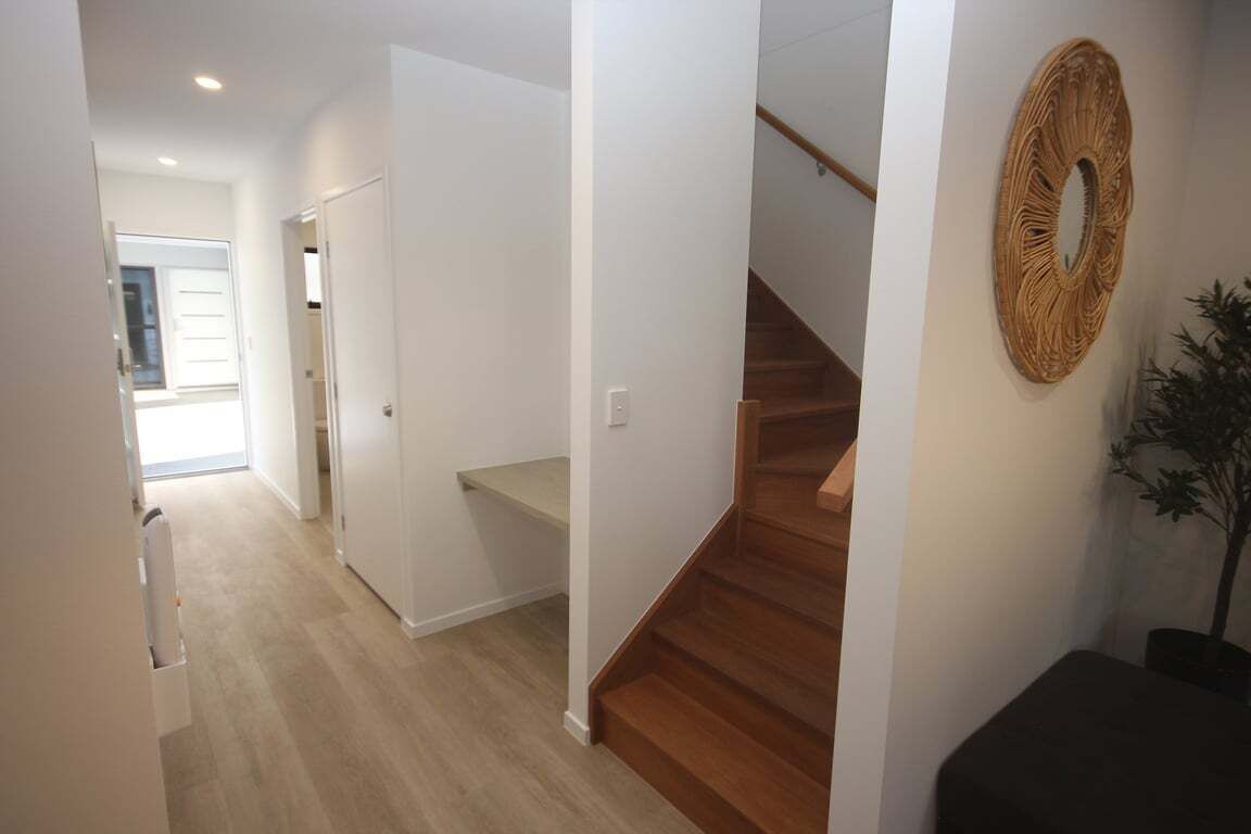 A hallway with a staircase leading to a landing, a door, and a wall-mounted decorative item.
