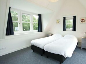 Quarto com duas camas, uma janela e uma mesinha de cabeceira.