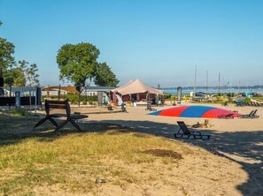 Uma praia com uma tenda, cadeiras de praia e uma bandeira.