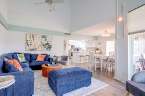 A spacious living room with a blue sofa set, a coffee table, and a dining area with white furniture. - Private Dock, Lake-View Deck! Point Venture Home (Leander)