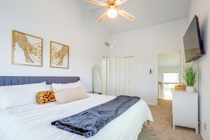 Ein Schlafzimmer mit Bett, Deckenventilator, Fernseher und Bildern an der Wand.