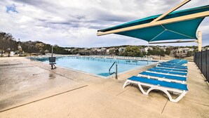 En swimmingpool med liggestole og et solbeskyttet område.