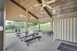 An outdoor patio area with picnic tables, ceiling fans, and a view of the surrounding park. - Private Dock, Lake-View Deck! Point Venture Home (Leander)