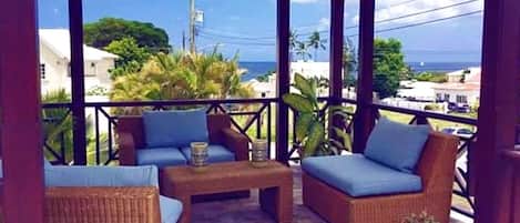 A covered outdoor seating area with wicker furniture and a tiled floor.