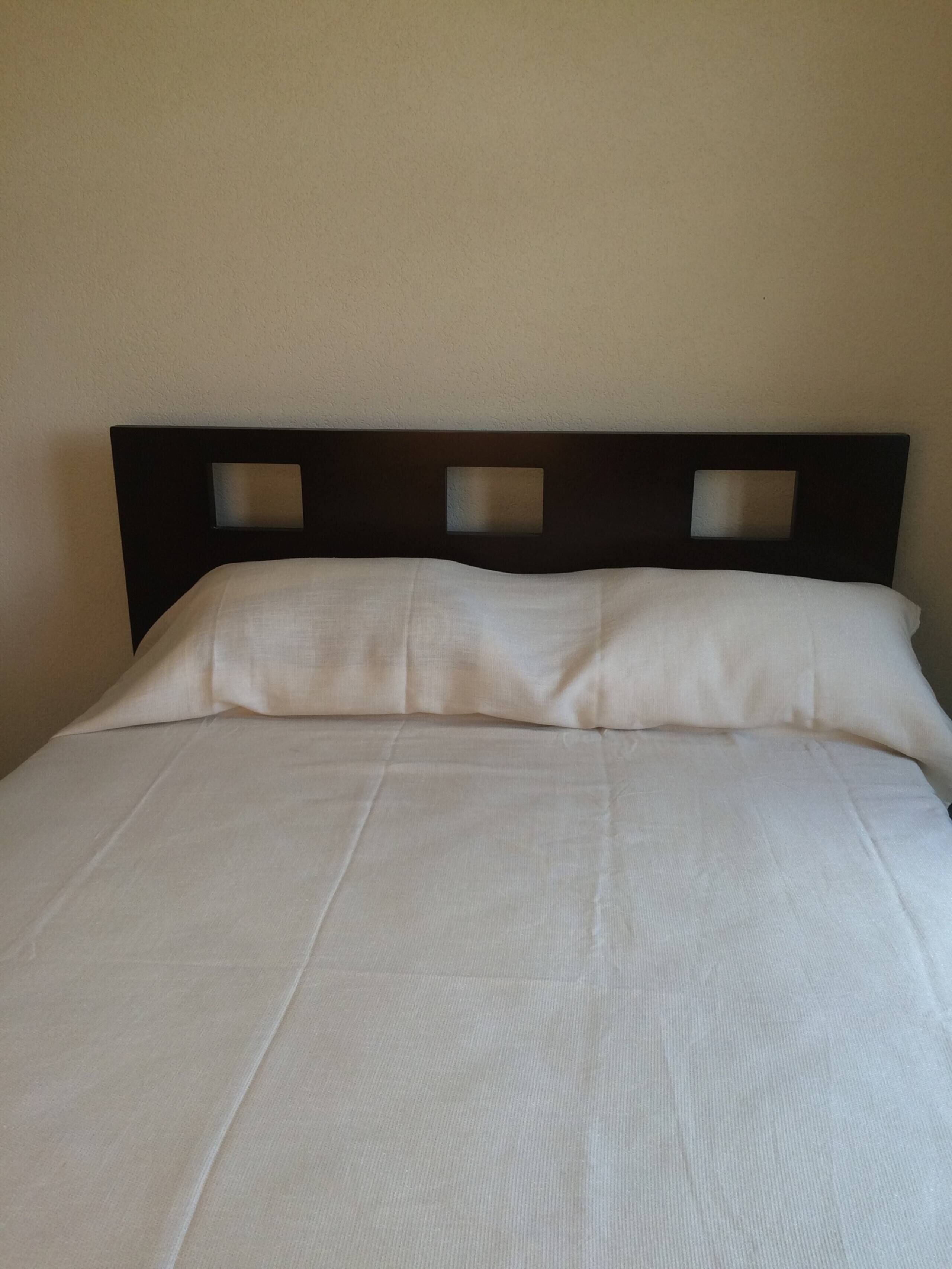 Un letto con una testiera scura e biancheria da letto bianca.