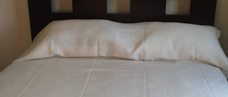 Un letto con una testiera scura e biancheria da letto bianca.