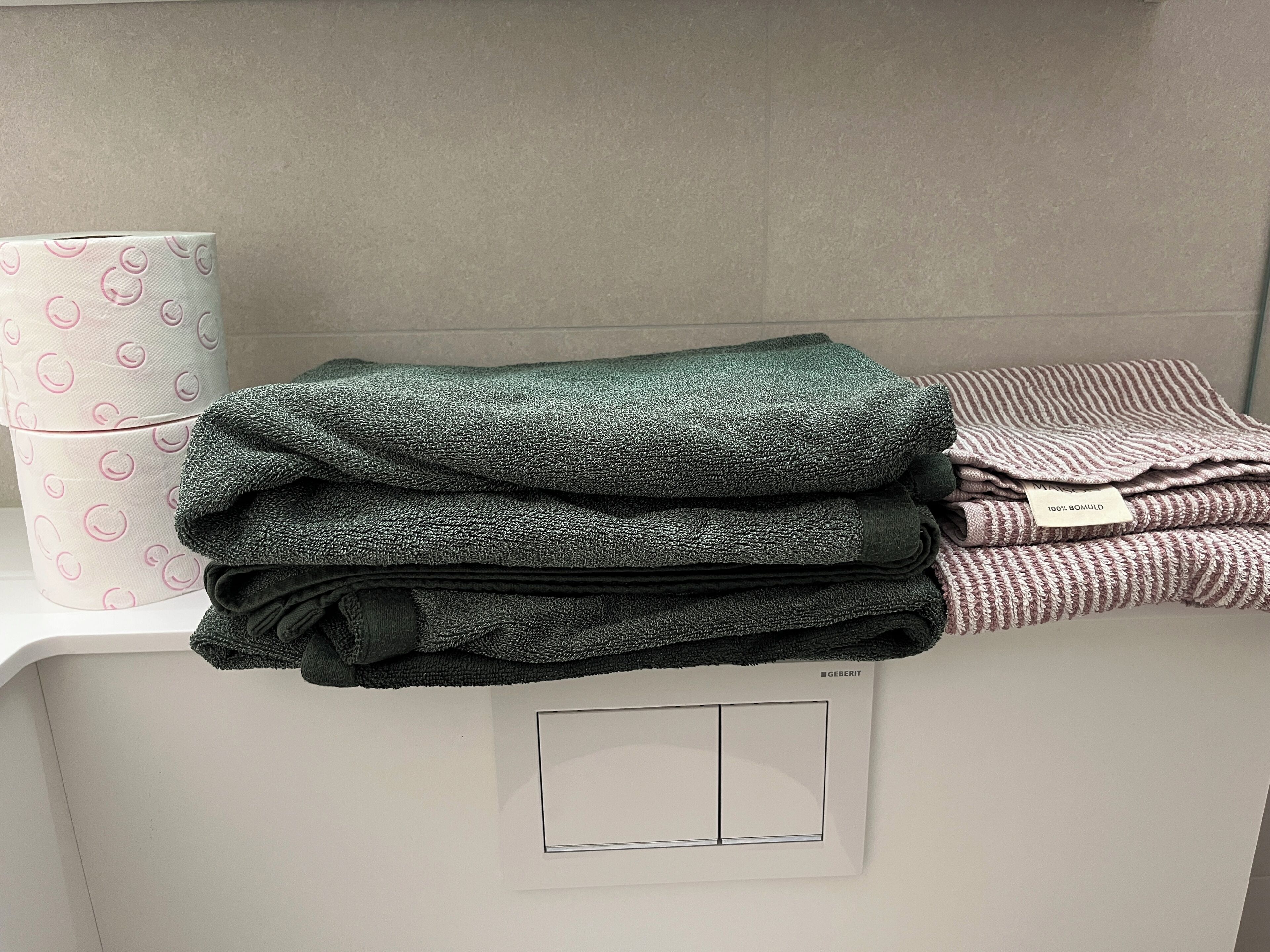A stack of folded towels in various colors on a white counter.
