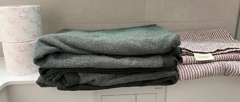 A stack of folded towels in various colors on a white counter.