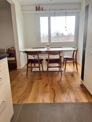 Una cocina con una mesa de comedor y sillas, suelo de madera y un ventanal con vistas.