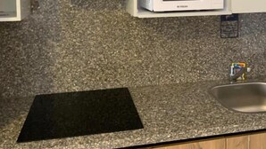A kitchen with a microwave, a black countertop, and a stainless steel sink. - La prestigia Hurghada Apartment (Red Sea Governorate)