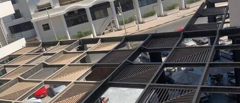 Un hotel de varios pisos con una terraza en la azotea que ofrece asientos al aire libre y vistas a un edificio blanco con minaretes.